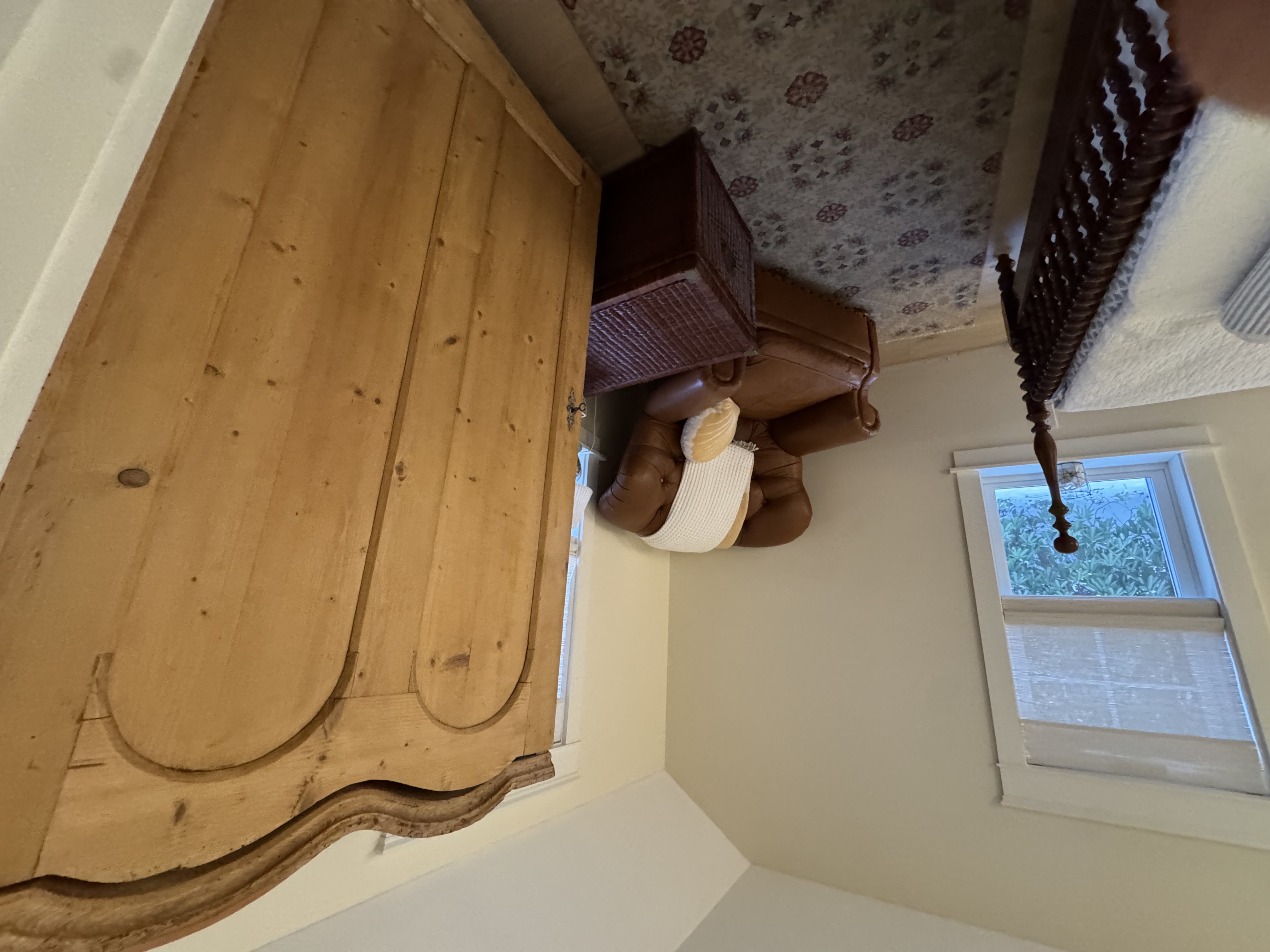 Primary bedroom sitting area with leather armchair and pine armoire