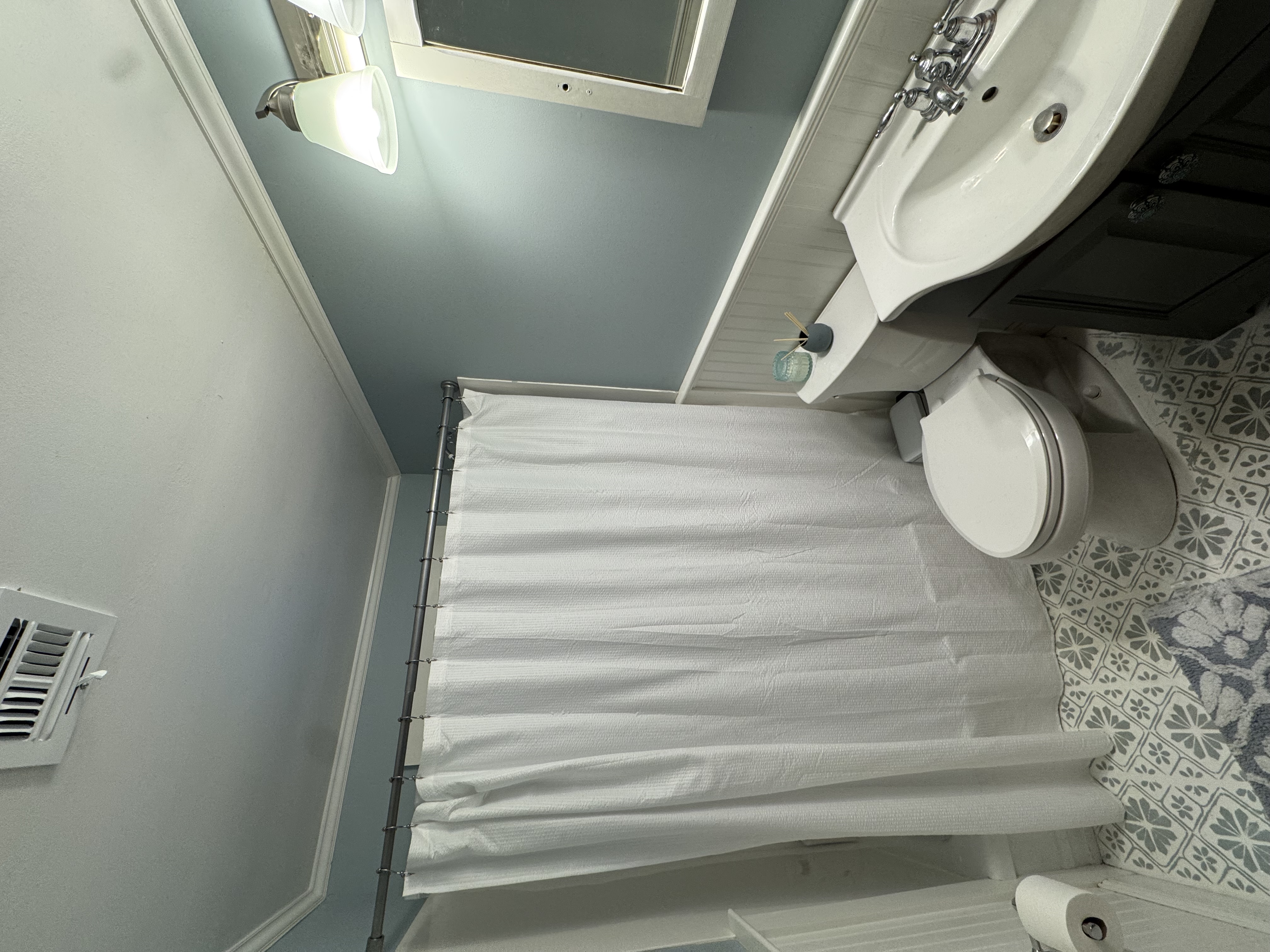 Bathroom with blue walls, beadboard, and patterned tile floor