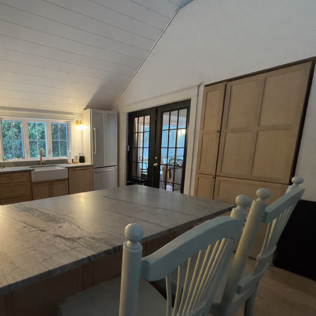Kitchen island with quartzite surface, dining seating, and French doors to porch