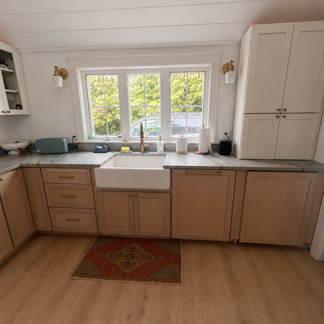 Farmhouse sink with brass fixtures, quartzite counters, and garden view