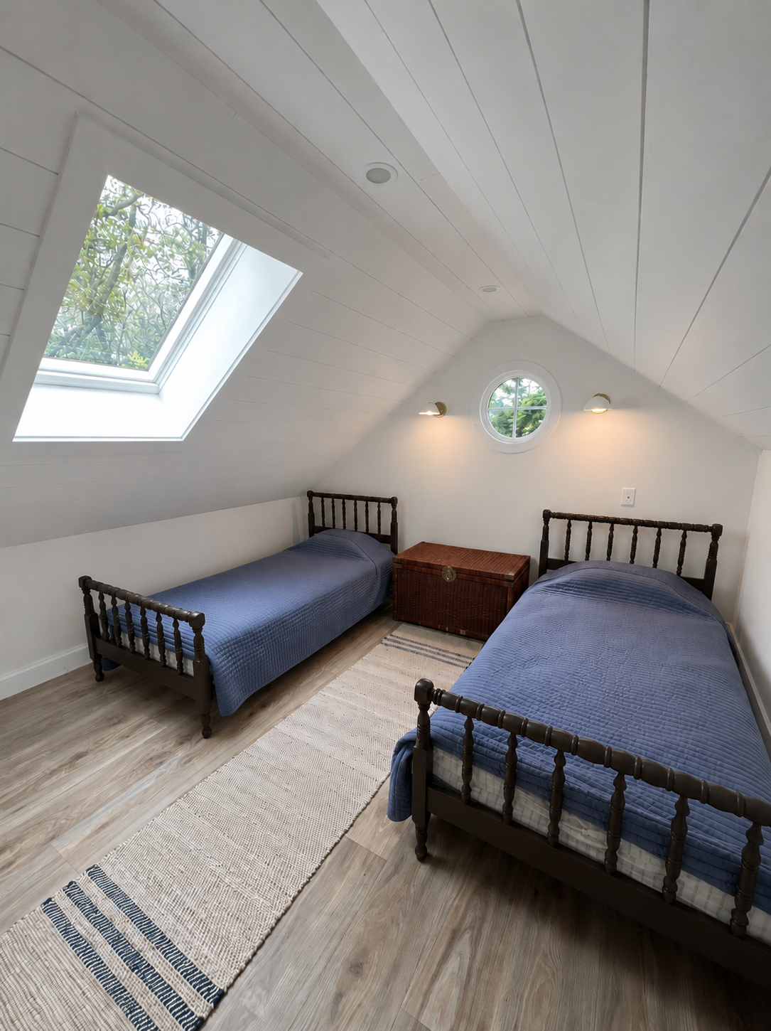 Loft bedroom with twin beds, skylight, and porthole window
